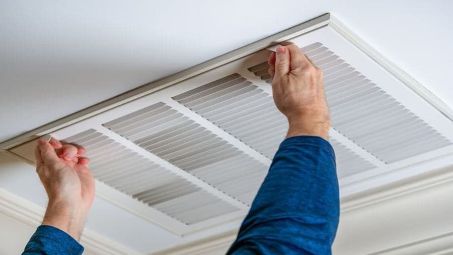 Technician adjusting an AC ceiling vent